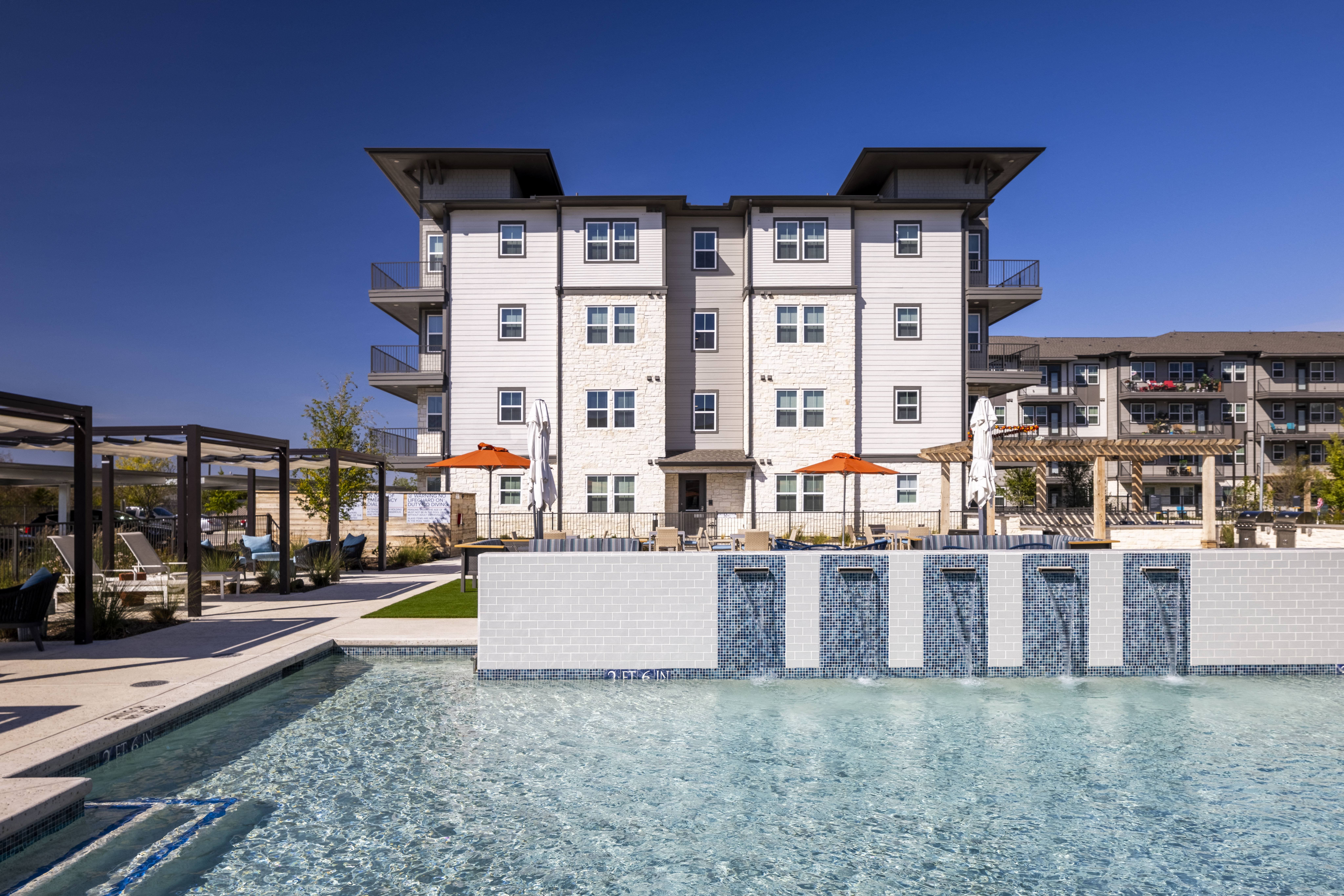 a ground-level view of resort style pool and apartment building at a senior apartment community